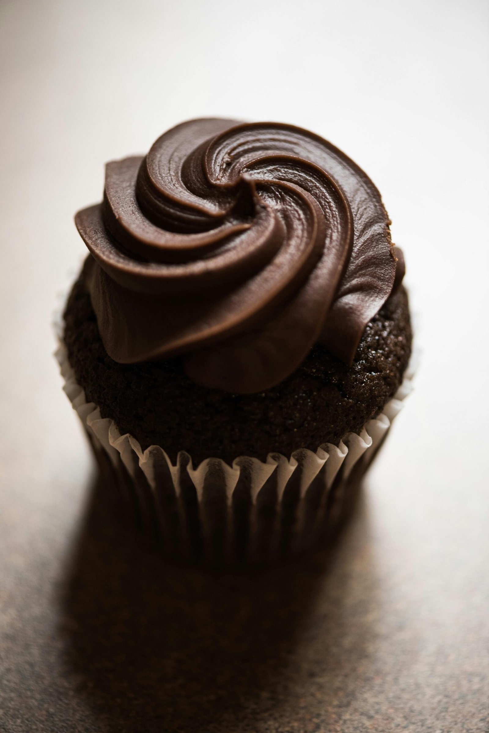 Delicious chocolate cupcake topped with rich, creamy frosting in a cozy indoor setting.